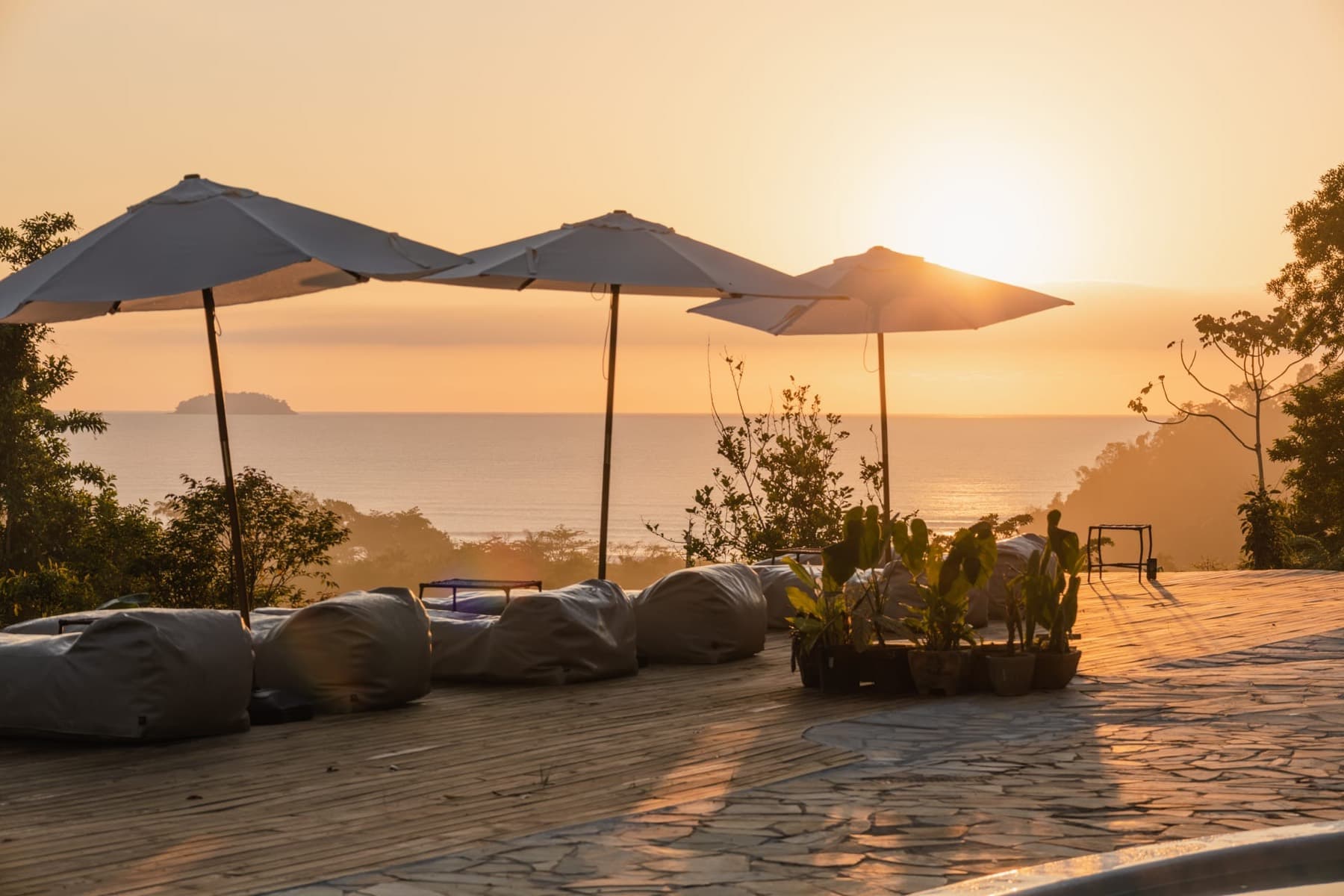 Deck com guarda-sóis e vista para o mar ao pôr do sol